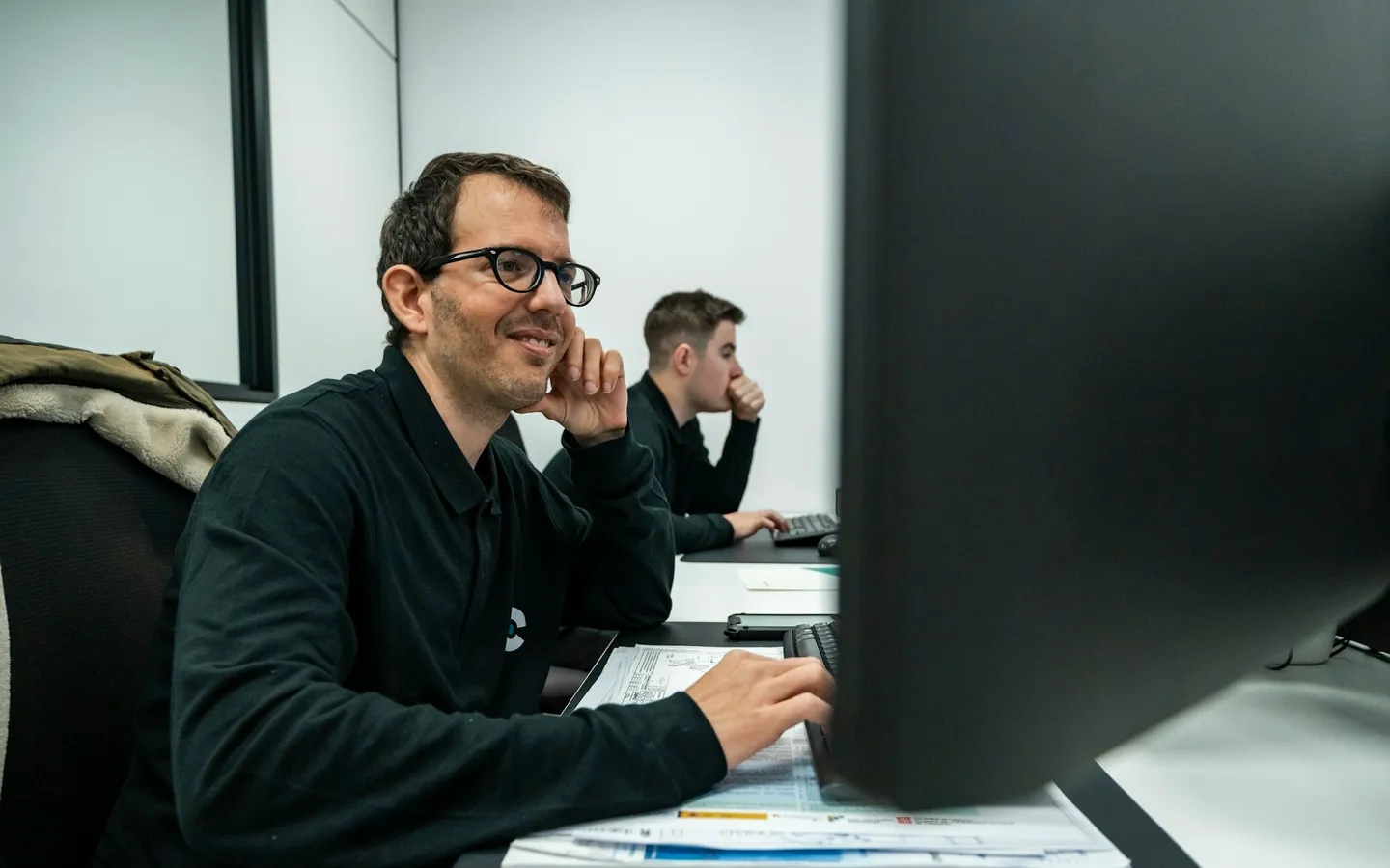Engineers reviewing technical drawings at computer workstations
