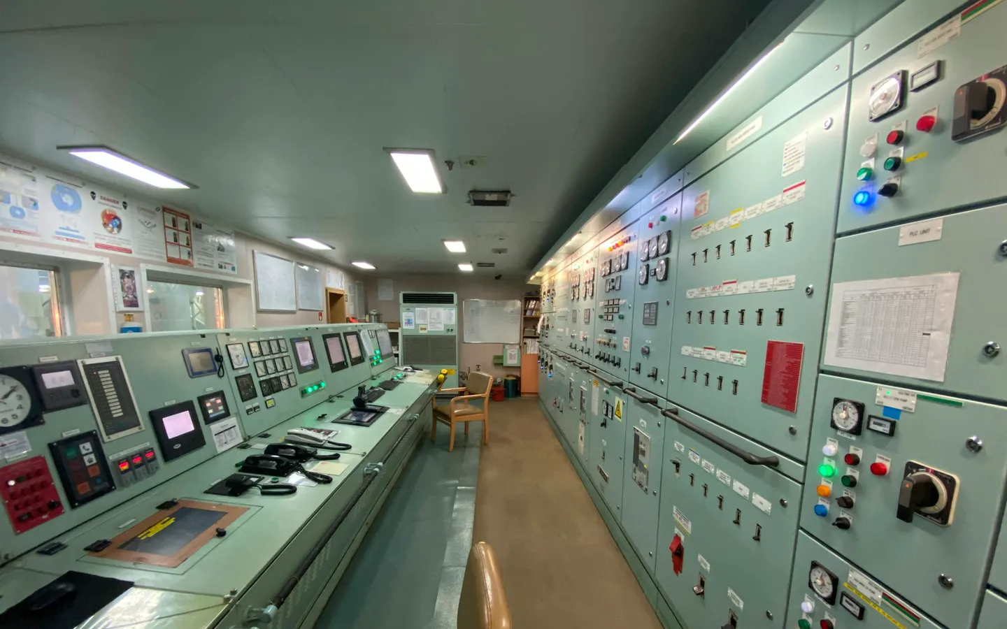 Ship engine control room with monitoring panels and control consoles